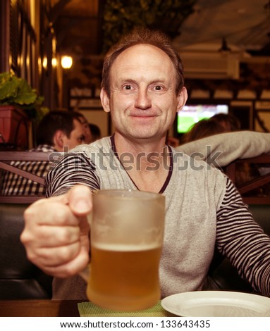 Happy aged man eating grilled sausages and beer