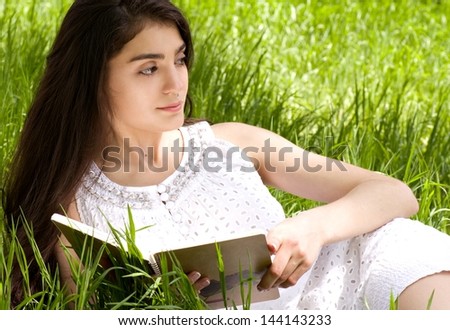 Beautiful young woman reading book in spring garden