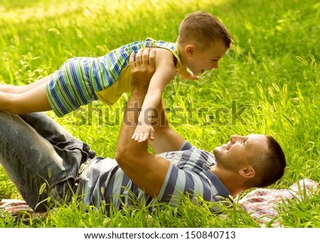 Father and son playing on green field