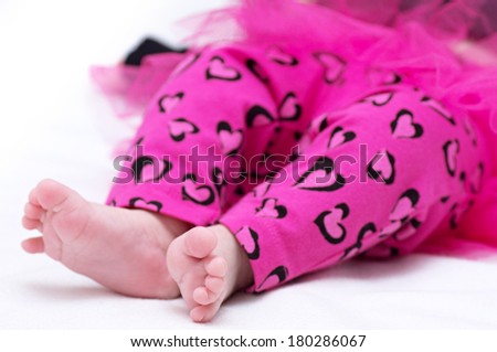 Newborn baby girl feet in pink clothes