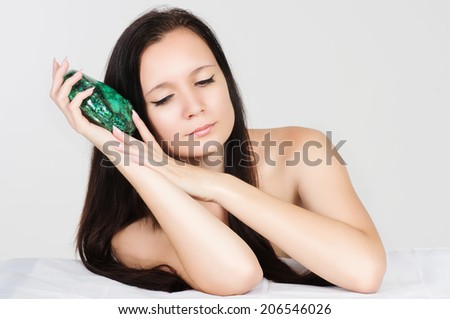 Beautiful young woman with exotic green shell on white background