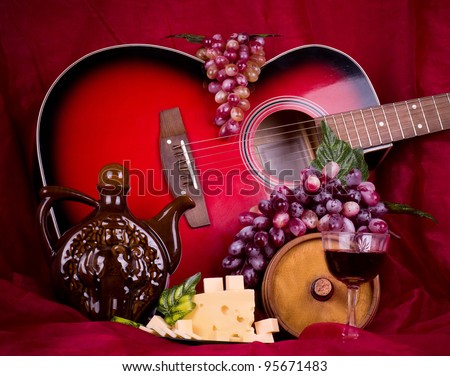 Beautiful composition with wine, grape, cheese and guitar on red background