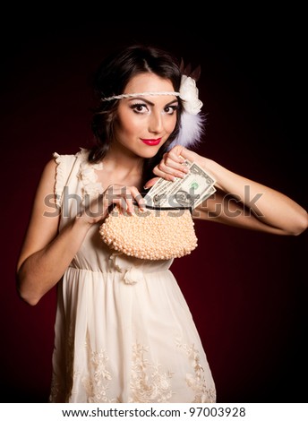 Vintage woman in retro dress with dollars on dark background. Pin-up girl