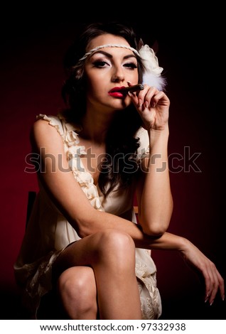 Vintage woman in retro dress with cigar on dark background. Pin-up girl