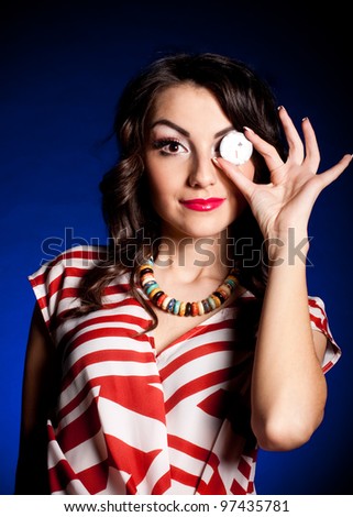 Beautiful young woman with casino chip on dark background