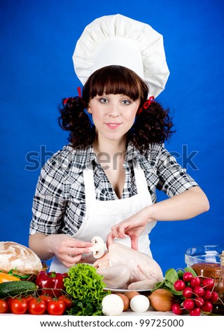 Smiling happy cook woman holds a Crude Hen with food ingredients