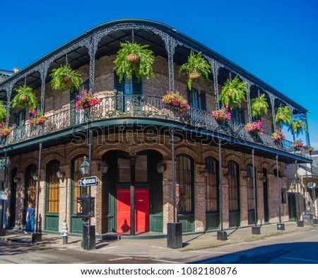 French Quarter architecture in New Orleans, Louisiana. House in French Quarter in 18th century Spanish style with cast iron galleries with hanging plants and pastel colors.