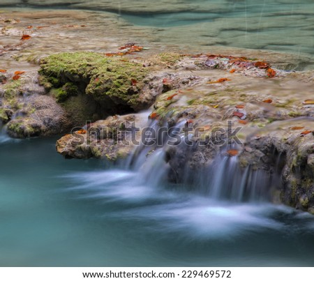 Small cascades in a mountain creek, smooth water surface.Nature untouched background. Karst formation.