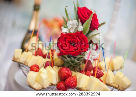 Pineapple and strawberries decorated with red roses and white flowers
