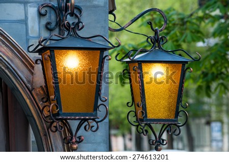 Two brass lanterns on a green background