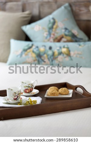 Decorative tray with tea set and flower on the bed
