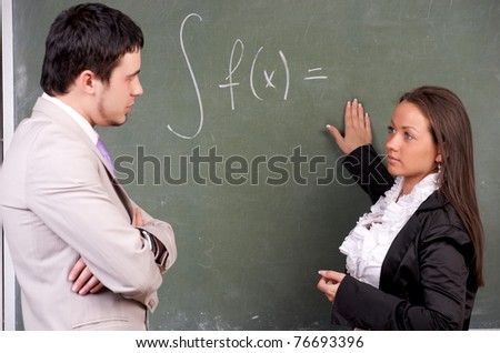 Young teacher and student doing exercise on blackboard