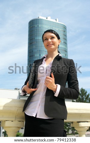 Portrait of attractive business woman in suit carrying laptop