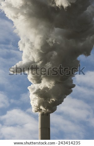 Large cloud of smoke from coal fired power plant against blue clouded sky