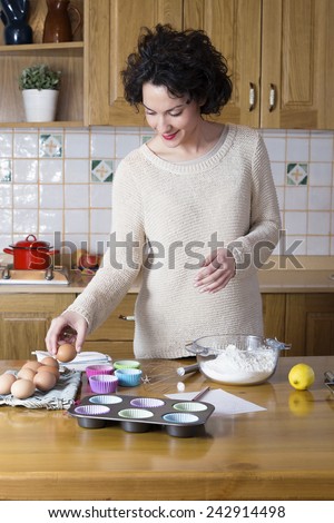 Attractive woman taking an egg to make a cupcakes recipe. Modern housewife cooking homemade traditional cupcakes in a rustic kitchen