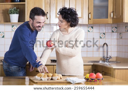 Man taking delicious cupcake while her woman offering him an apple. Concept of healthy food. Concept of temptation and meal