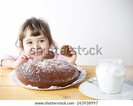 Adorable little girl eating a homemade chocolate cake. Very happy and cute toddler taking a piece of  delicious cake