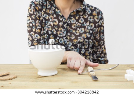 Funny woman throwing a lump of sugar to milk. Cute woman having breakfast of milk and biscuits