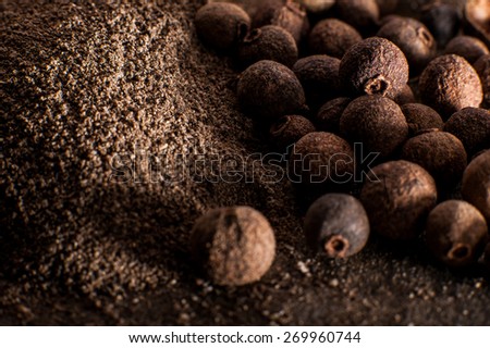 Layer of allspice peppers close-up and ground pepper
