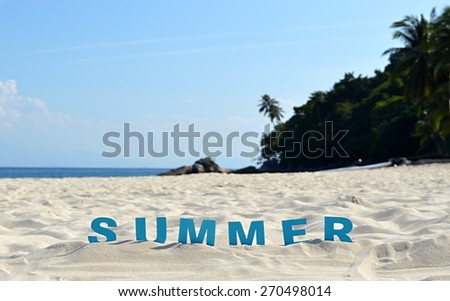 The word summer spelled out with blue letters in the sand at a tropical beach