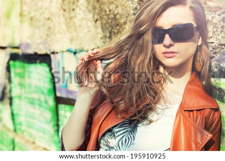 beautiful brunette girl in sunglasses standing around the walls with graffiti