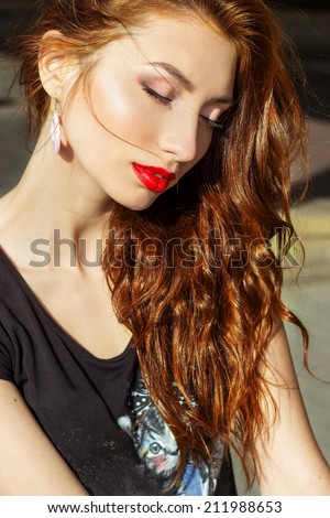 beautiful sexy girl with red hair with big red lips with makeup in the city on a Sunny summer day