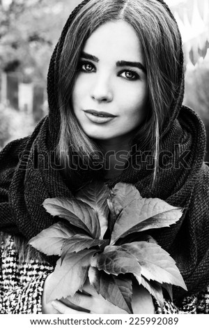 beautiful charming young attractive girl with large blue eyes with a handkerchief on his head, long dark hair holding a fall bouquet of leaves on a cold autumn day