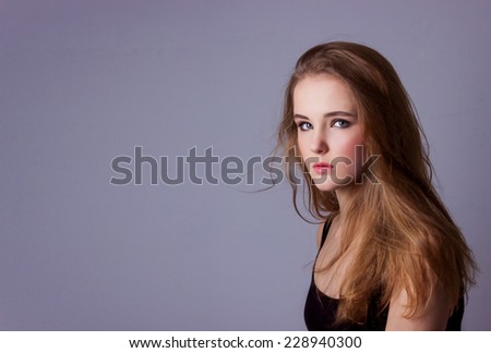 young, beautiful girl in a black t-shirt. Professional model posing in Studio on white-gray background. Take a model test of a young pretty girl.