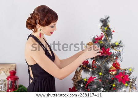 beautiful sexy happy smiling young woman in evening dress with bright makeup with red lipstick, decorates a Christmas tree for the new year
