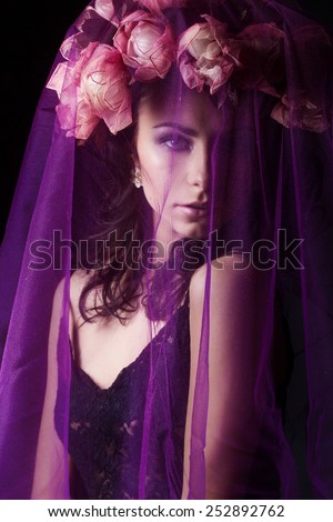 beautiful sexy girl with black hair in a black lace dress with a wreath on his head covered with a violet veil in the Studio on a black background, beauty portrait