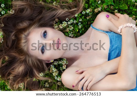 beautiful sexy girl with bright makeup is lying on the grass and flowers on a Sunny summer day