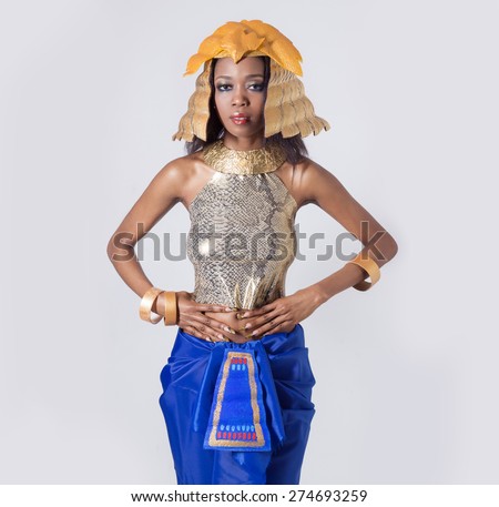elegant beautiful dark-skinned woman in a suit of the Egyptian queen Cleopatra in gold tones with bright makeup