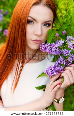 beautiful sexy woman with fiery regime hair with eyes of a Fox in the garden with lilacs