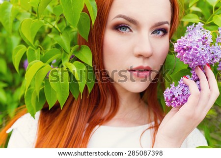 beautiful cute sexy red-haired girl with long hair in a white dress with a bouquet of lilac in the hands of