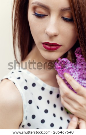 beautiful sexy sweet girl with a sprig of lilac in the hands and shirt with polka dots
