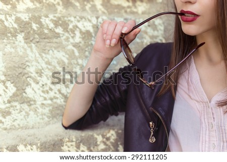 girl with red lipstick in a black leather jacket sunglasses bit