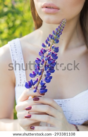 beautiful sexy woman in white sundress holding lupine flower in the hands