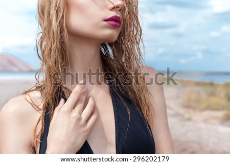 beautiful sexy cute girl in a fashion shoot in a bathing suit in desert dry cracked earth in the background of the mountains under the sky on a sunny summer day,  model proportionally