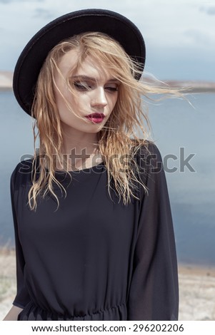 fashion photo of young beautiful sexy girl with wet hair in a black hat and a black cotton dress with beautiful bright makeup, model proportionally