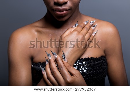 Beautiful hand of the girl with dark skin on the shoulders of graft of acrylic nails with nail unusual fotmoy