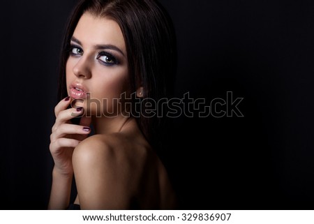 fashion portrait of beautiful sexy young girl with full lips bright makeup black Smokey eyes with black long hair in Studio on a black background