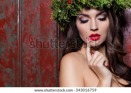 Christmas elegant fashion woman. Xmas New Year hairstyle and makeup. Gorgeous Vogue style Lady with Christmas decorations on her head, baubles, professional makeup, red lipstick long red evening dress