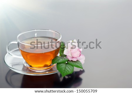 Transparent cup with green tea and fresh herbal bouquet on mirror background