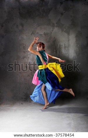 Young modern dancing girl in colorful dress on the dirty grunge  grey studio background
