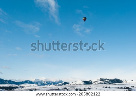 Flying in a hot air balloon over mountains in snow in a sunny day in winter. Relaxing and enjoying the ballooning experience!