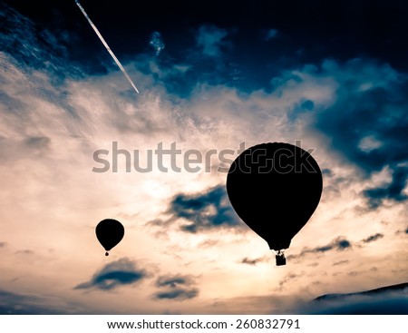 Hot air balloons taking off into a dark blue sky in a sunrise with beautiful clouds in the background. A relaxing ballooning flying experience for vacation.