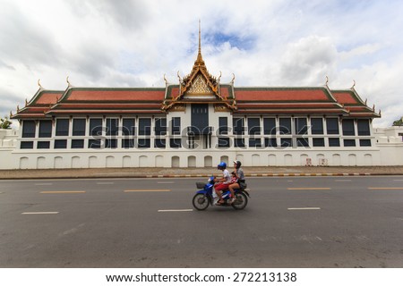 BANGKOK, THAILAND - SEPTEMBER 31, 2013: A family make school run by motorbike on a busy city road in front of the famous Buddhist Temple Wat Phra Kaew, one of the main landmarks of Bangkok, Thailand