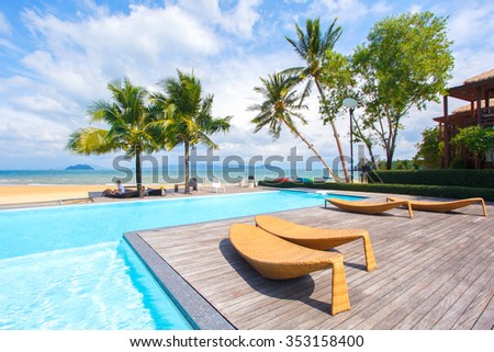 Summer, Travel, Vacation and Holiday concept - Umbrella and chair with pool in hotel resort