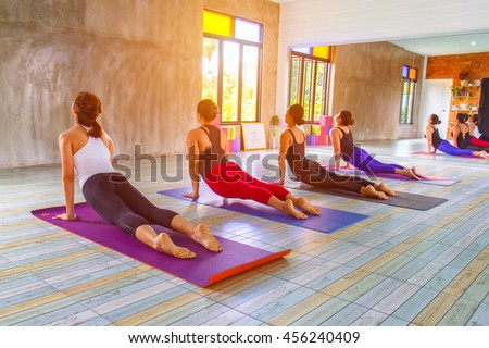 Fitness asian female group doing warm up yoga pose in row at the yoga class. selective focus