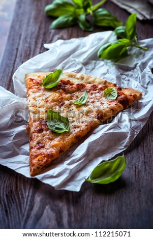 Slice of cheese pizza topped with fresh basil